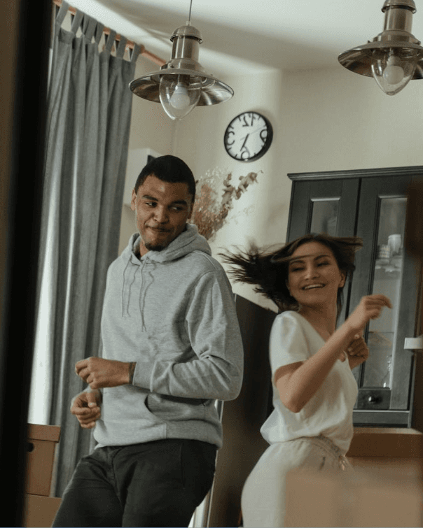 Two people dancing and laughing together in a living room